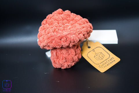 Pink plush mushroom toy with a tag on a black background