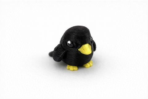 3D-printed penguin figurine with black body and yellow feet on a white background
