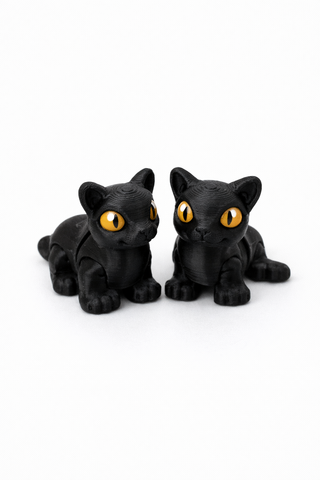 Two black cat figurines with yellow eyes on a white background
