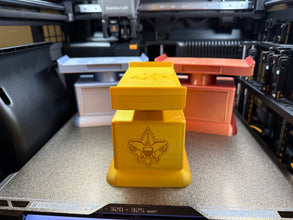 Three 3D printed trophies with a logo on a 3D printer bed