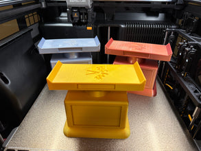 3D printed trophies in various colors on a 3D printer bed.