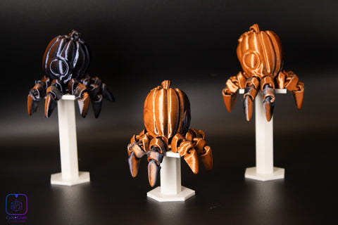 Three pumpkin and octopus-like figures on stands against a dark background