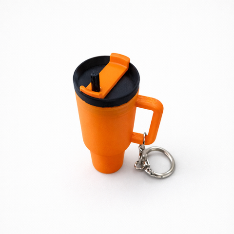 Orange mug-shaped keychain with black lid on a white background